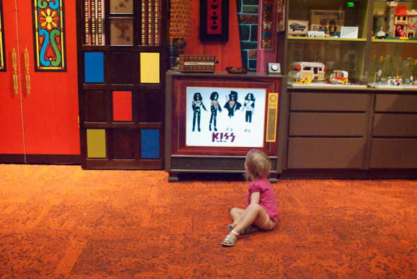 Sitting on the floor watching a commercial for KISS figurines on TV  